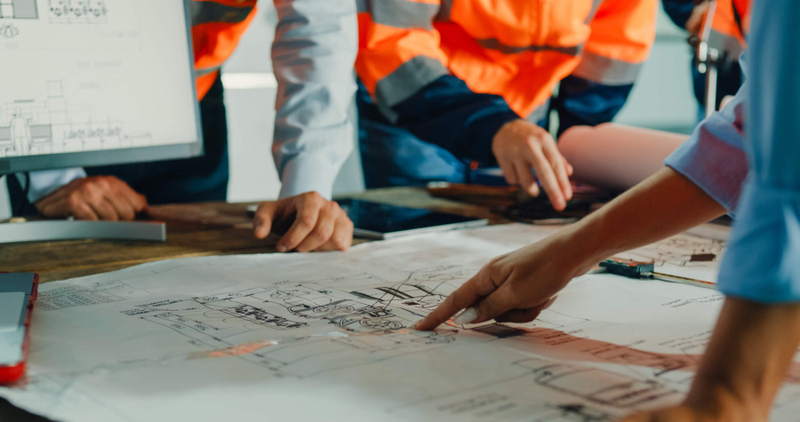 Engineering team Architectural plans on a table and hands pointing at them.