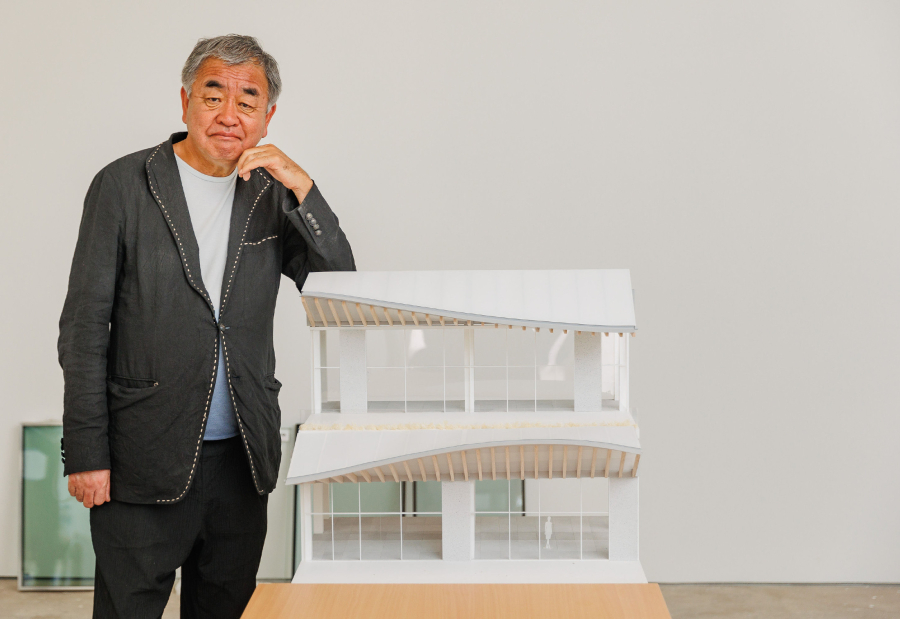 O Κένγκο Κούμα όρθιος και πλάι του μακέτα της Riviera Galleria σε λευκό χρώμα.