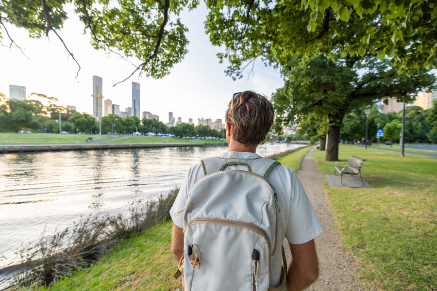 A man walks leisurely through the city, looking around, with his mobile phone in his bag.  