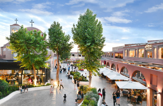 Άνθρωποι σε εξωτερικό διάδρομο με δέντρα και παρτέρια, δεξιά και αριστερά εστιατόρια και πίσω εκκλησία.