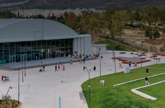 Γκρίζο υπόστεγο με γυάλινη πρόσοψη με εισόδους. Τριγύρω ανοικτός χώρος με γρασίδι. 