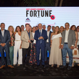 Άνθρωποι μπροστά από λογότυπο Fortune. Στο κέντρο ο CEO Οδυσσέας Αθανασίου με βραβείο, δεξιά ο Κωστής Χατζηδάκης. 